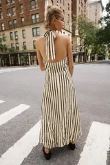 Vestido midi de cuello halter anudado, escote en pico y espalda descubierta, con diseño a rayas verticales y bajo abullonado con elástico interior.