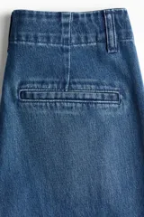 Pantalón de jean de tiro alto con corte wide leg y piernas amplias. Presenta diseño con raya frontal marcada, cierre con botón oculto, bolsillos laterales al bies y bolsillos traseros decorativos.