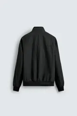 Cazadora azul marino de corte regular fit, confeccionada en tejido técnico repelente al agua. Presenta cuello subido, manga larga, bolsillos de vivo en cadera, bolsillo interior y acabados en rib en puños y bajo. Cierre frontal de cremallera oculta por solapa con botones a presión.