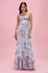 Vestido largo Patbo de color celeste con estampado floral, escote palabra de honor (strapless), diseño con corset translúcido y falda larga con múltiples volados.