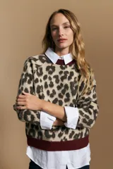 Sweater de tejido jacquard con estampado animal print, de silueta relajada y manga larga. Presenta cuello redondo y bordes en contraste de color bordó.