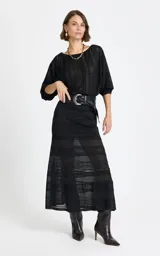 Blusa negra de encaje con hombros caídos, mangas tres cuartos con puños ajustados y diseño de paneles verticales texturizados.