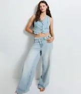 Chaleco de jean con escote en V, cierre frontal con botones metálicos y ruedo redondeado. Presenta un diseño clásico con lazo ajustable en la espalda.