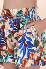 Short de playa con estampado botánico en tonos blanco, azul, verde y marrón. Presenta cintura elástica fruncida y corte estructurado con pliegues frontales.