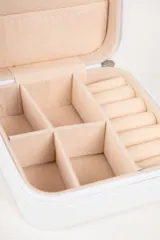 Caja organizadora de joyas blanca con interior de terciopelo color crema, con compartimentos para anillos, collares y aros.