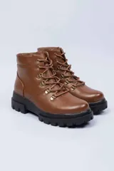 Botas estilo montaña de color marrón, con cordones frontales, ganchos metálicos y suela gruesa negra con plataforma y relieve.