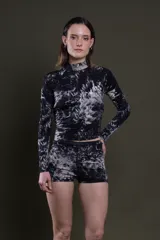 Remera de lycra estampada con patrón batik en blanco y negro, de corte ajustado, cuello alto y mangas largas.