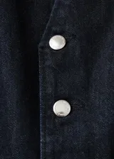 Mono largo de denim color negro, con cierre frontal de botones metálicos, bolsillos frontales y traseros, y perneras de corte recto.