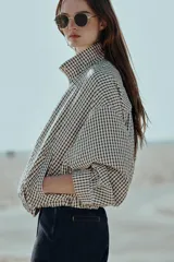 Chaqueta estilo bomber con estampado de cuadros vichy en blanco y negro, de cuello subido, manga larga y bolsillos delanteros de vivo. Cuenta con bajo abullonado y cierre frontal con cremallera oculta.