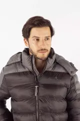 Campera puffer de diseño color block, combinando tonos azul oscuro y gris. Cuenta con capucha desmontable, cierre frontal de cremallera, cuello elevado y bolsillos laterales con cierre de botón.