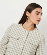 Campera de algodón con estampado cuadrille en tonos verde claro y blanco. Presenta cuello redondo, cierre frontal con botones, mangas largas con puños elásticos y bolsillos frontales tipo parche.