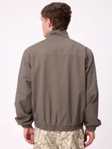 Campera Rusty de corte clásico, color negro, con cierre frontal completo, cuello alto y puños elásticos. Presenta un diseño minimalista con el logo de la marca bordado en el pecho.