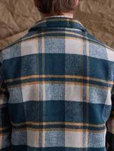 Chaqueta de lana con cierre frontal completo, diseño a cuadros en tonos azul marino y verde, cuello camisero y bolsillos laterales.