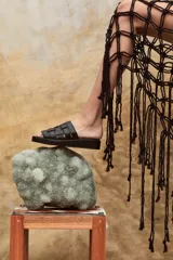 Sandalias bajas de cuero color dorado, con tiras tejidas en la parte superior y suela marrón.