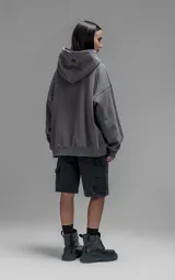 Hoodie oversize de corte crop, color gris oscuro, confeccionado en frisa de algodón. Presenta capucha forrada, bolsillo tipo canguro frontal y puños elásticos.