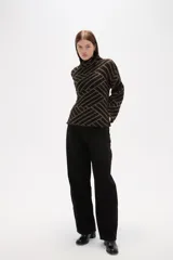 Sweater de tejido jacquard con diseño geométrico de líneas entrelazadas en tonos negro y marrón. Presenta cuello alto, mangas largas con terminación holgada y un corte recto.