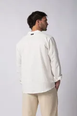 Camisa de manga larga confeccionada en lino, con cuello mao y cierre frontal de botones. Presenta un corte relajado y diseño minimalista.