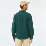 Camisa de manga larga de tejido gofrado en color verde oscuro, con cuello clásico, cierre frontal de botones y un bolsillo aplicado en el pecho.