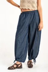 Pantalón tipo jean de corte wide leg y diseño balloon, con cintura elástica y cordones ajustables en los tobillos. Confeccionado en algodón denim de tono azul oscuro.
