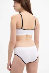 Bombacha tipo bikini color blanco con ribetes negros en las piernas, confeccionada en microfibra sin costuras de tiro medio.