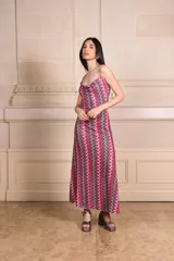 Vestido midi con estampado de ondas verticales en tonos fucsia, verde y plateado. Tiene breteles finos, escote drapeado y espalda baja.