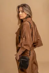 Bandolera compacta color rosado, con correa regulable y desmontable. Tiene apertura superior, bolsillo frontal con cierre y detalle de borla, y bolsillo trasero sin cierre. El interior está forrado en tela y cuenta con un bolsillo adicional.