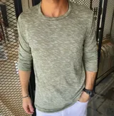Buzo fino de punto jaspeado en color verde militar, con cuello redondo y mangas largas.