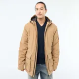 Parka ligera color beige con capucha ajustable, cierre frontal con cremallera y parche decorativo con texto en la manga.