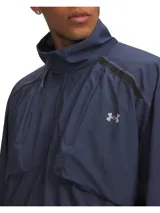 Buzo deportivo Under Armour modelo Unstpbl Wvn HZ Solid, color azul marino, con cierre frontal de media longitud, cuello alto y bolsillos frontales flotantes en el pecho.
