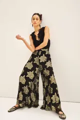 Pantalon de corte amplio y tiro alto, confeccionado en tejido jacquard negro con estampado floral en hilo metalizado dorado. Presenta una silueta fluida y holgada.