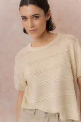Sweater tejido celeste de manga corta con textura y delicadas líneas horizontales en relieve. Presenta cuello redondo y calce amplio con hombros caídos.
