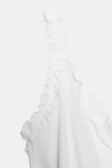 Top de tirantes con escote en pico, detalle de volantes en los hombros y bajo con volado fruncido que aporta volumen.