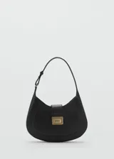 Bolso de hombro tipo hobo en color negro, con diseño curvo y cierre frontal mediante solapa con hebilla metálica dorada. Cuenta con un asa ajustable y forro interior con bolsillo con cremallera.