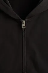Campera con capucha y cierre de cremallera metálica, corte oversize, hombros caídos y bolsillos delanteros tipo canguro, en tejido negro de algodón.