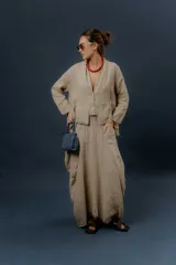 Pollera larga de lino color gris topo, de diseño amplio con volumen, movimiento y bolsillos delanteros. Cuenta con elástico en la cintura y detalles de pinzas y sobretelas en los laterales.