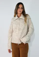 Campera de tejido de punto con diseño jaspeado en tonos beige y marrón. Presenta cuello alto con cierre frontal completo, mangas largas y puños acanalados.