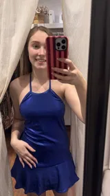 Vestido corto color rojo metalizado, con escote halter, tiras para atar al cuello y falda con volado en el ruedo.