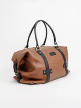 Bolso de viaje grande de cuero marrón con detalles en cuero negro, doble asa de mano y tiras decorativas verticales.
