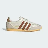 Championes Adidas modelo Japan, reedición de diseño clásico de 1964. Presentan un empeine de piel perforada en color crema con las icónicas tres bandas laterales en tono marrón. Incluyen refuerzos de gamuza en la puntera y el talón, junto con una suela de goma en tono amarillento que aporta un estilo vintage.