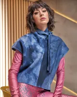 Chaleco de lana merino afieltrada, con grandes hombros y entallado a la cintura. El cuello es un lazo que se puede anudar de infinitas maneras. El color "azules" es único, renace del teñido artesanal con la técnica Tie Dye permitiendo descubrir diferentes matices y acuarelas únicas.