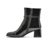Bota de vestir Korium modelo Sandy, de caña media en cuero negro con acabado brillante. Presenta una tira decorativa delgada con hebilla metálica alrededor del tobillo y un taco cuadrado de altura media.