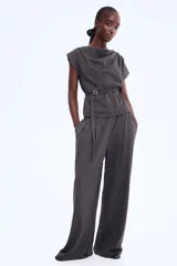 Top de manga corta color gris oscuro, con escote tipo capa o drapeado y un cinturón fino con hebilla metálica cuadrada que ajusta la cintura.