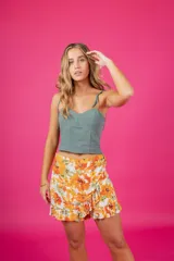 Short con diseño de pollera, tiro medio, estampado floral en tonos violeta, azul y rosado. Presenta detalle de aro de madera en la cintura, cierre lateral oculto y volados en la parte inferior.