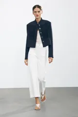 Pantalón de jean blanco de tiro alto y corte wide leg, con bolsillos delanteros y traseros. Cierre frontal con cremallera y botón metálico.