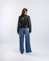 Campera estilo motero de símil cuero color negro, con cuello alto, cierre frontal asimétrico, bolsillos con cierre y detalles acolchados en los hombros.