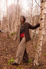 Pantalón de sastrería con diseño bicolor asimétrico, combinando una pierna en color marrón oscuro y la otra en beige, ambos con un sutil estampado de rayas diplomáticas. Presenta una silueta de corte recto y relajado, con cierre frontal y botón de nácar.