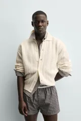 Cárdigan de ajuste relajado, tejido en hilado con lana, color crema. Presenta cuello solapa, manga larga y textura de punto trenzado en todo el cuerpo. Cierre frontal con botones.