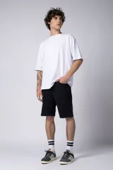 Bermuda de jean color negro lavado, de corte regular y largo a la rodilla, con dobladillo doblado en el ruedo.