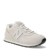 Championes urbanos New Balance modelo 574, color marfil, confeccionados en gamuza y malla con detalles texturizados en la puntera. Presentan el logo N característico en los laterales y suela con diseño moteado.