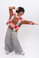 Buzo de punto con diseño geométrico de cuadros en tonos marrón, celeste, rosa y rojo. Presenta cuello redondo, puños y ruedo en color crema, con mangas largas y corte recto.